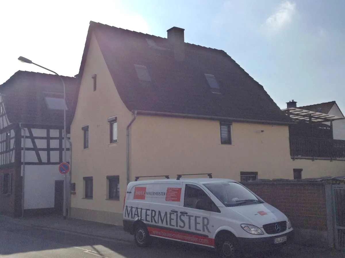 Firmenwagen von Bauer Malermeister vor einem frisch gestrichenen Einfamilienhaus